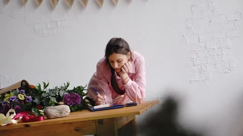 Florist girl writes notes in a notebook and counts on the calculator behind the Stock Footage 86885976