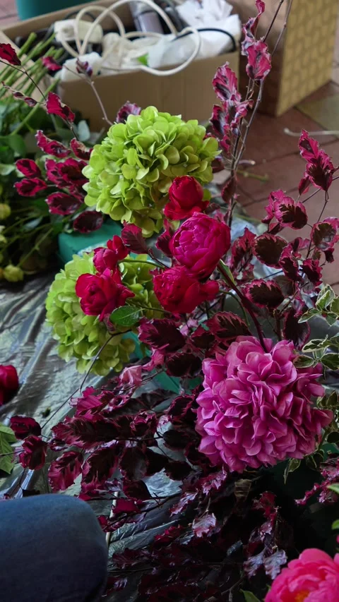Florist inserts a red rose into a romantic burgundy wedding flower arrangement. Stock Footage 318558127