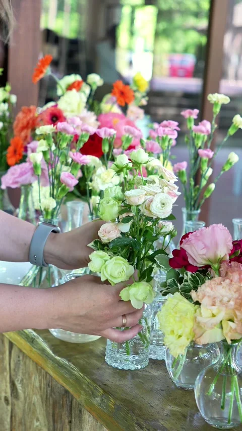 Florist inserts rose spray into small vases forming bouquets. Wedding decor and Stock Footage 318558107