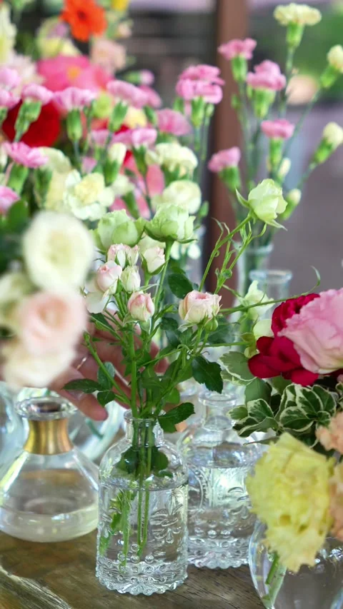 Florist inserts rose spray into small vases forming bouquets. Wedding decor and Stock Footage 318558140
