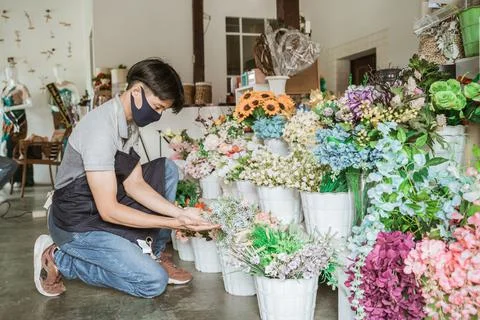 Florist man using face mask checking a flower bouquet Stock Photos