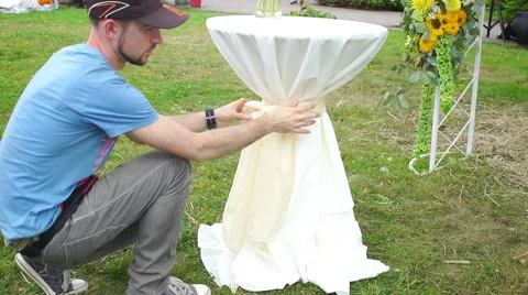 Florist man at work tying a bow on white table. Stock Footage 65923563
