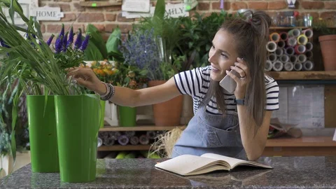 Florist preparing bouquet for client and checking order off notebook Stock Footage 94573379