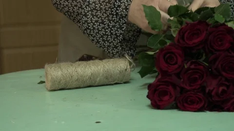 The florist processes and makes a bouquet of scarlet red maroon roses Stock Footage 123684929