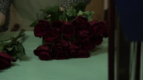 The florist processes and makes a bouquet of scarlet red maroon roses Stock Footage 123684959