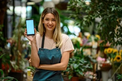 Florist showing a smartphone while surrounded with flowers and plants in a fl Stock Photos