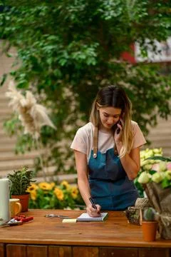 Florist talking with client on the smartphone and taking an order in a flower Stock Photos