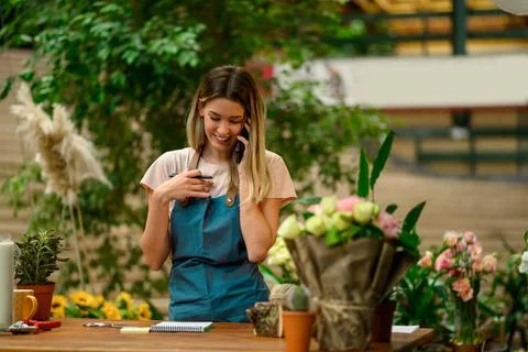 Florist talking with client on the smartphone and taking an order in a flower Stock Photos