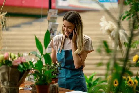 Florist talking with client on the smartphone and taking an order in a flower Stock Photos