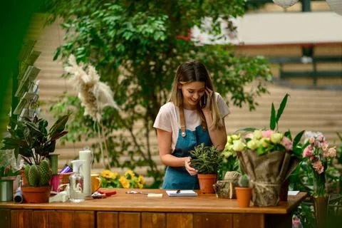 Florist talking with client on the smartphone and taking an order in a flower Stock Photos
