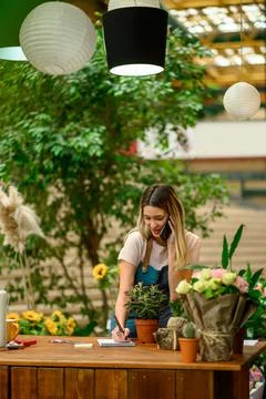 Florist talking with client on the smartphone and taking an order in a flower Stock Photos