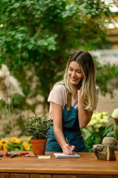 Florist talking with client on the smartphone and taking an order in a flower Stock Photos