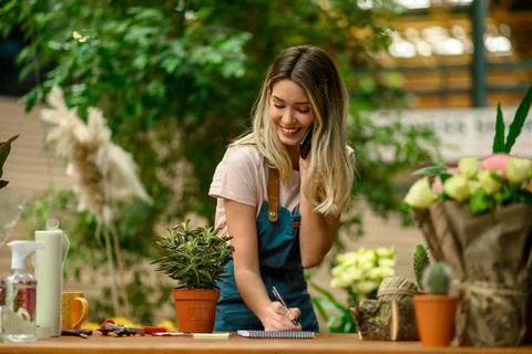 Florist talking with client on the smartphone and taking an order in a flower Stock Photos
