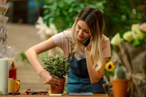 Florist talking with client on the smartphone and taking an order in a flower Stock Photos