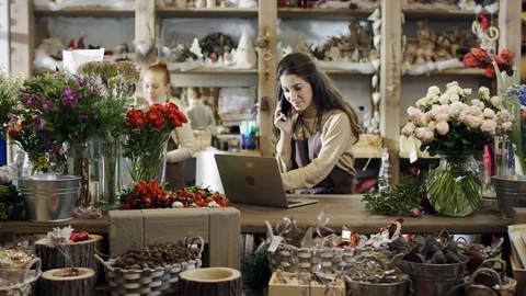 Florist talking by the phone and writes something in her laptop Stock Footage 101783689