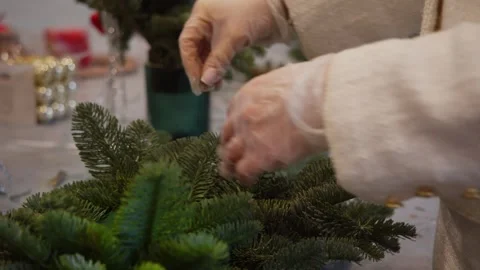A florist, wearing gloves, carefully inserts a fir twig into the base of a Stock Footage 316069509