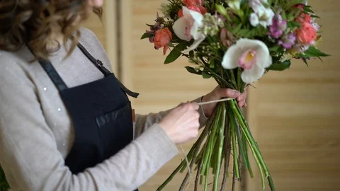 Florist at work: pretty young blond woman holds fashion modern bouquet of Stock Footage 87113084