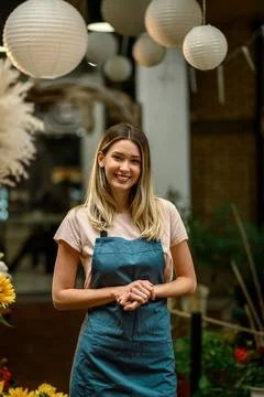 Florist working in flower shop while smiling and looking at a camera Stock Photos