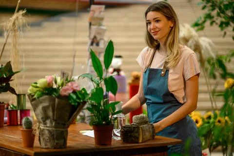 Florist writing in notebook while leaning against counter in a flower shop Stock Photos