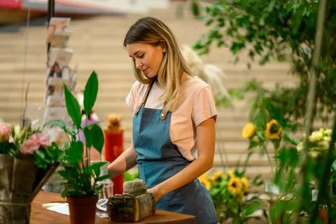 Florist writing in notebook while leaning against counter in a flower shop Stock Photos