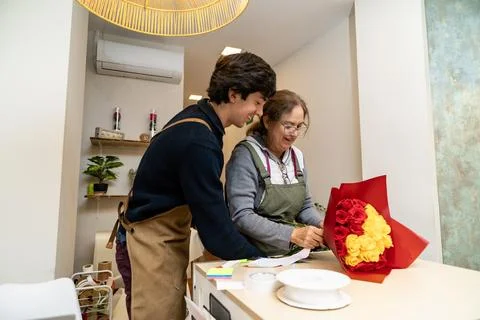 Florists collaborating creating custom rose bouquet in shop Stock Photos