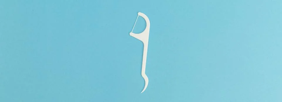 Floss with plastic handle on blue background Stock Photos