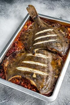 Flounder flat fish roasted in a tomato sauce in baking tray. White background Stock Photos