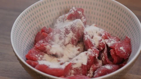 Flour being added and mixed into diced beef Stock Footage 121449422