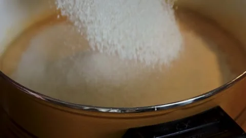 Flour being sifted through a metal sieve into smooth batter in a saucepan. Stock Footage 340897036