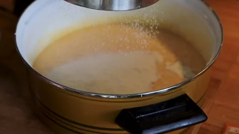 Flour being sifted through a metal sieve into smooth batter in a saucepan. Stock Footage 340897158