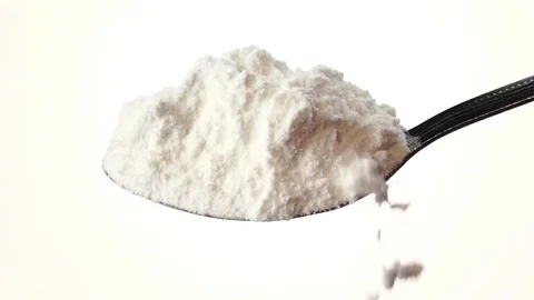 Flour extra class falling from the iron spoon. White background. Slow motion Stock Footage 75525049