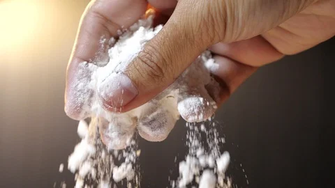 Flour falling from hand in slow motion on black background. Stock Footage 124038367