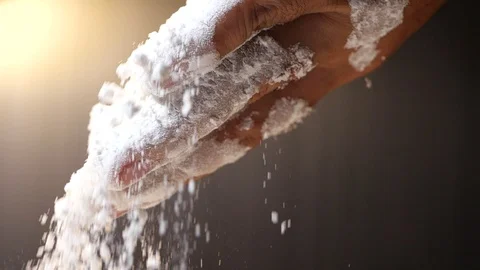 Flour falling from hand in slow motion on black background. Stock Footage 126077007