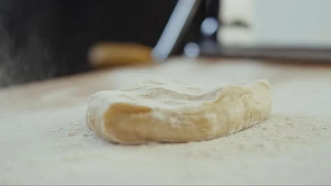 Flour falling on piece of dough on a table Stock Footage 274613424
