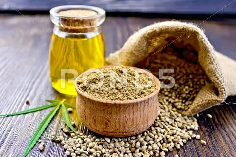 Flour hemp in bowl with grain and oil on board Stock Photos