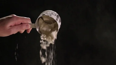 Flour Pouring From Measuring Cup Against Black Background In Slow Motion Stock Footage 82149146