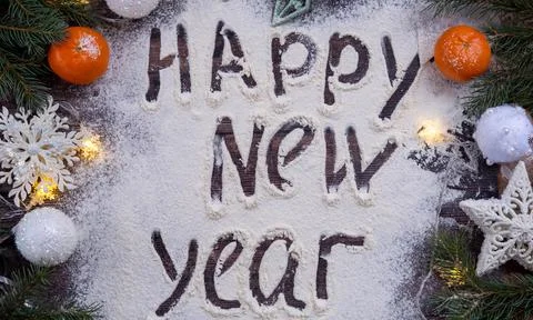 Flour is scattered on a wooden table, next to fir branches, tangerines and Stock Photos