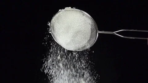 Flour sift through sieve, black background. Slow motion, bottom view Stock Footage 75486526