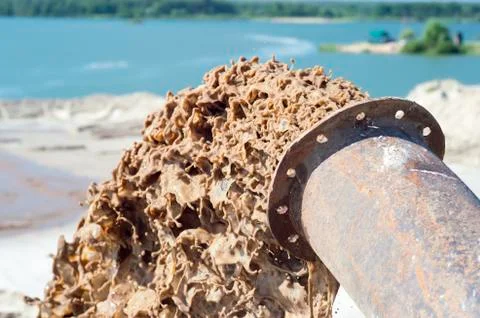 The flow of brown liquid from the pipe close-up on the background of the lake Stock Photos
