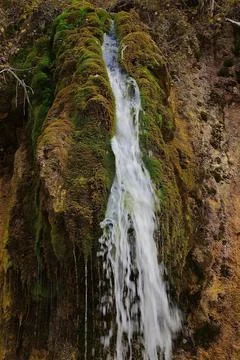 The flow of cold and clean spring water of the Plakun waterfall on the right  Stock Photos