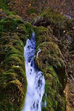 The flow of cold and clean spring water of the Plakun waterfall on the right  Stock Photos