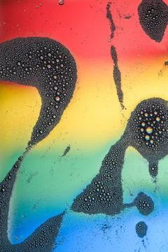 The flow of foam with a lot of small bubbles against the rainbow background. Stock Photos