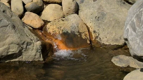 Flow of hot water containing sulfur through rocks Stock Footage 292932668