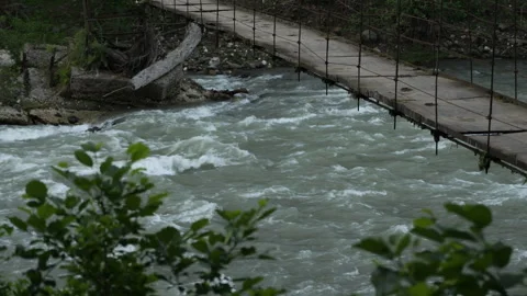 The flow of a mountain river and a bridge Stock Footage 328125754