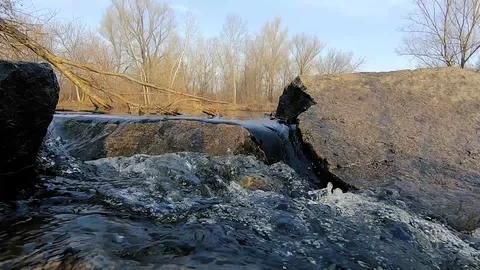 The flow of the river between the stones. A stream of water with bubbles.  Video stock 104432671