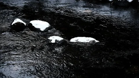The flow of the river in slow motion among the snowdrifts and rocks with snow Stock Footage 126537294