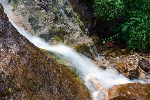 The flow of a small waterfall on the rock flows over the stones Stock Photos