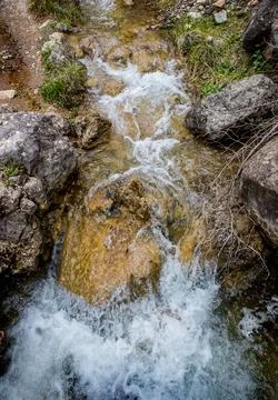 Flow of water between the rocks of a mountain stream Stock Photos