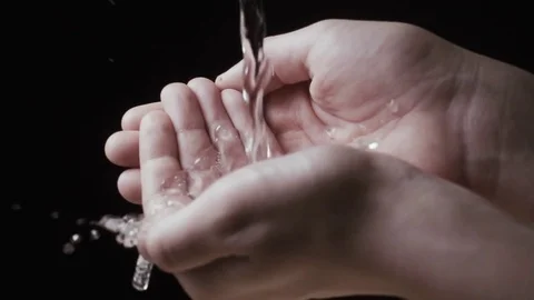Flow of water in children's hands on a black background. Slow mo Stock Footage 74761742