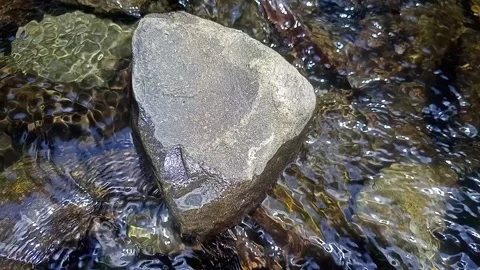 The flow of water meanders through the rocks of the river Stock Footage 237359242
